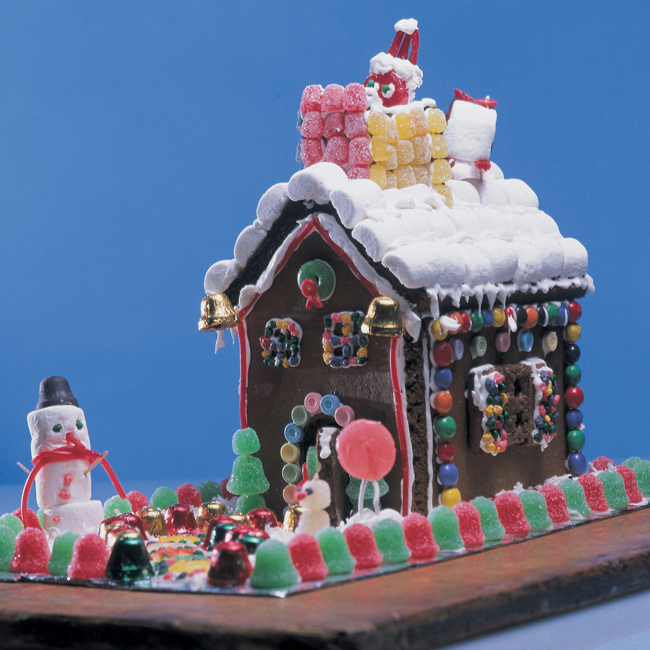 homemade gingerbread house with gumdrop fence and snowman