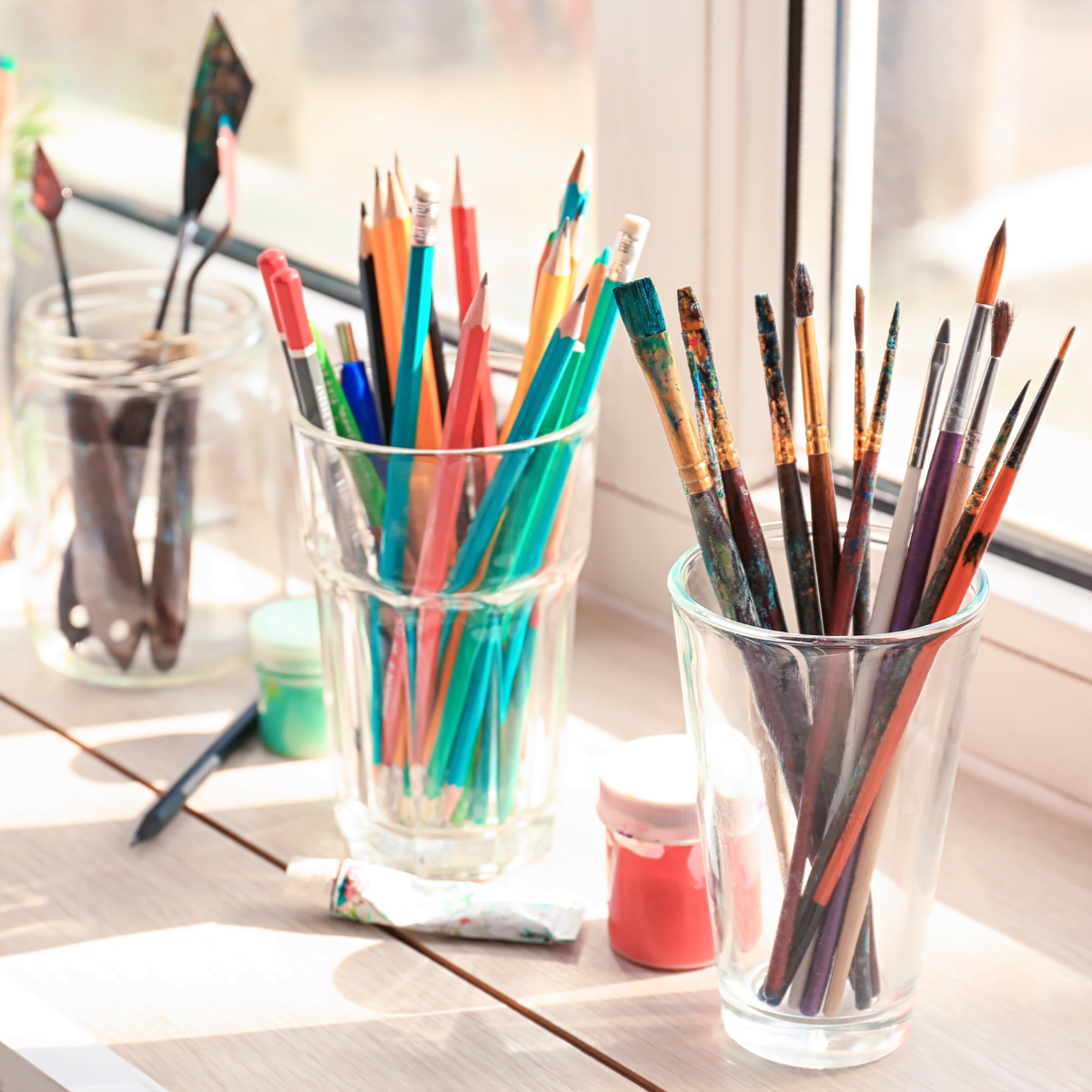 pencils and paint brushes in clear cups