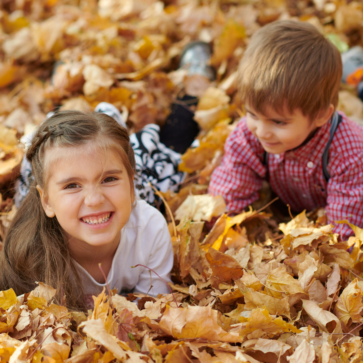 girl and boy in fall leaves