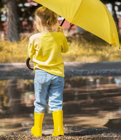 girl standing outside wearing rainboots and holding an open umbrella
