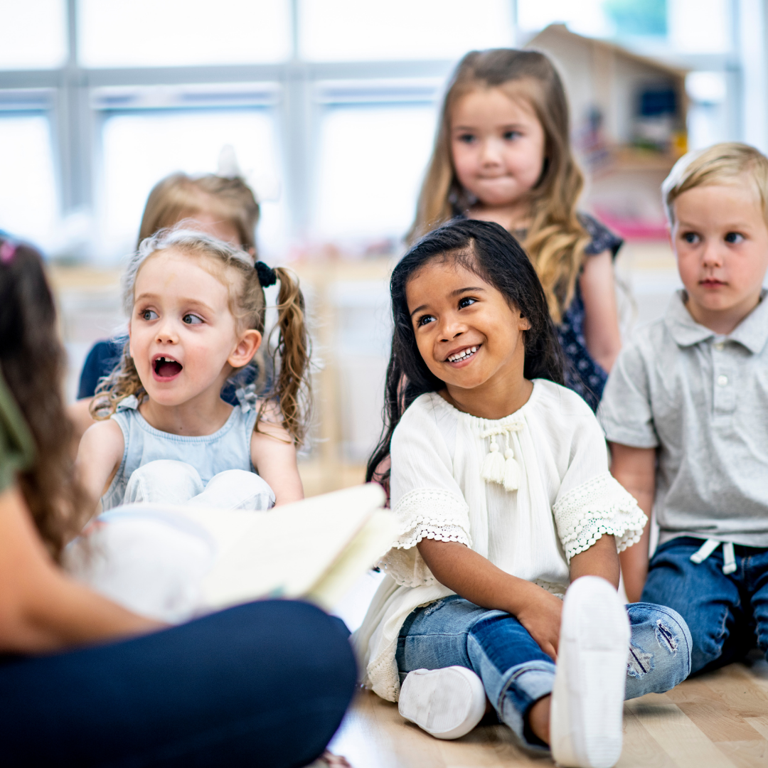 young children sitting in the floor listening to a story