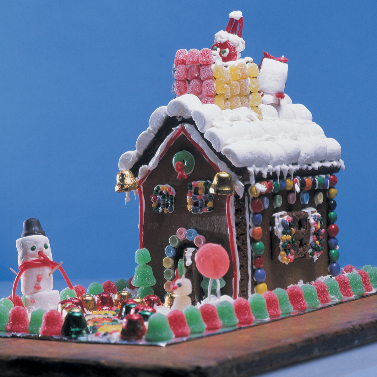 homemade gingerbread house with gumdrop fence and snowman