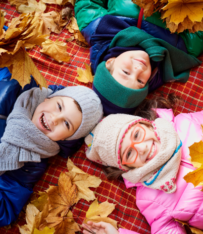 kids in fall leaves with a blanket